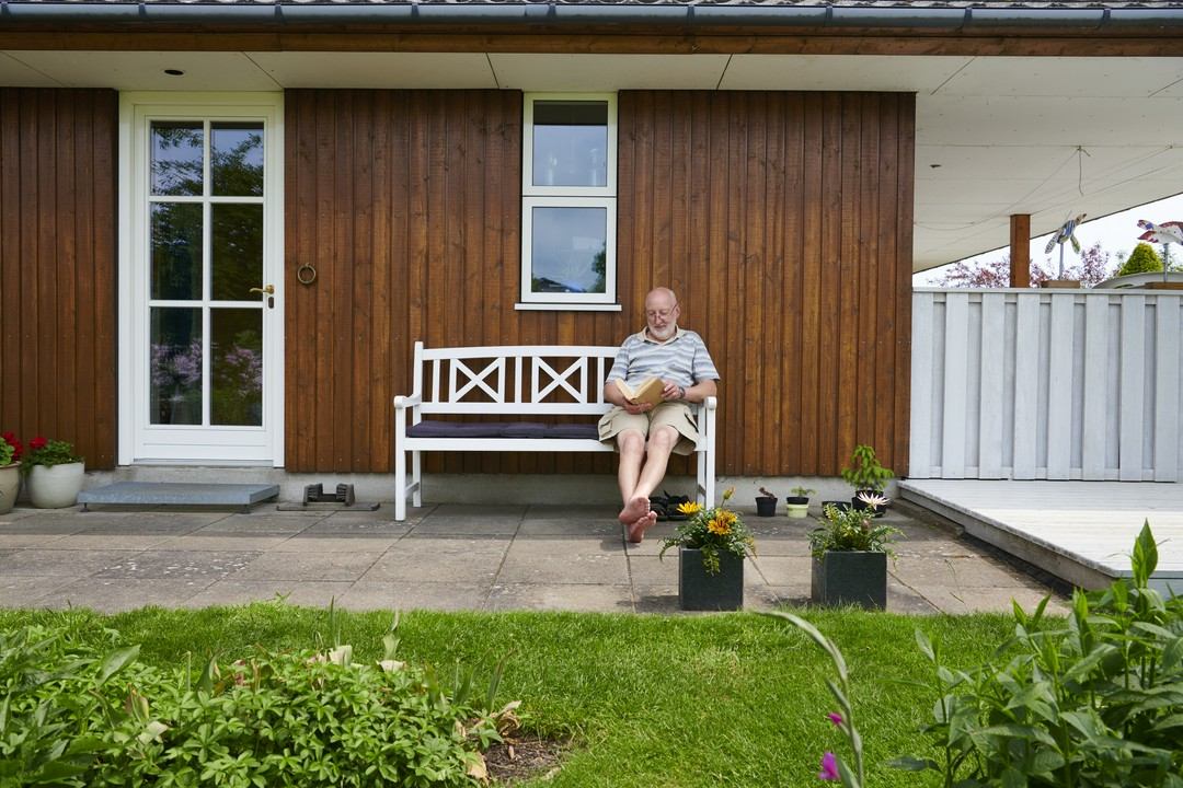 emeryt siedzący przed domem na ławce